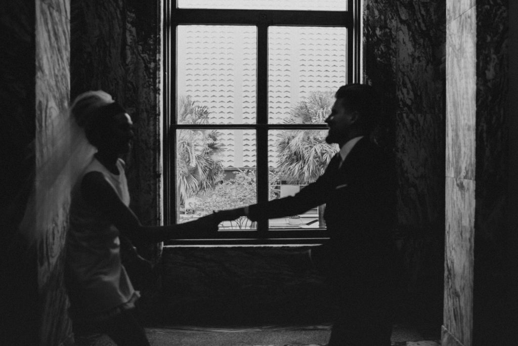 Bride and groom dancing in front of window
