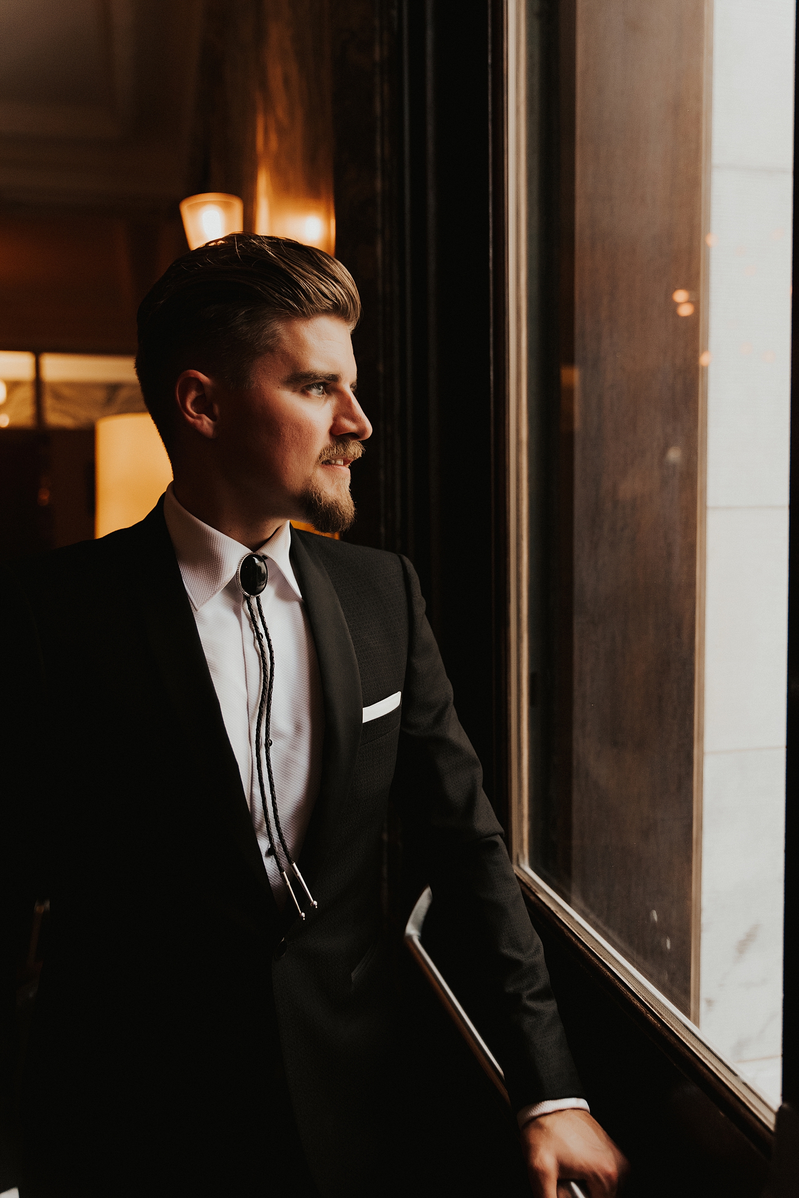 Groom in bolo tie looking out window at Le Meridien tampa