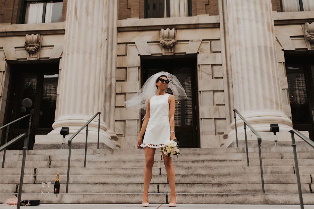 Blue brothers inspired bridal portrait of bride in short white dress on Le Meridien Steps