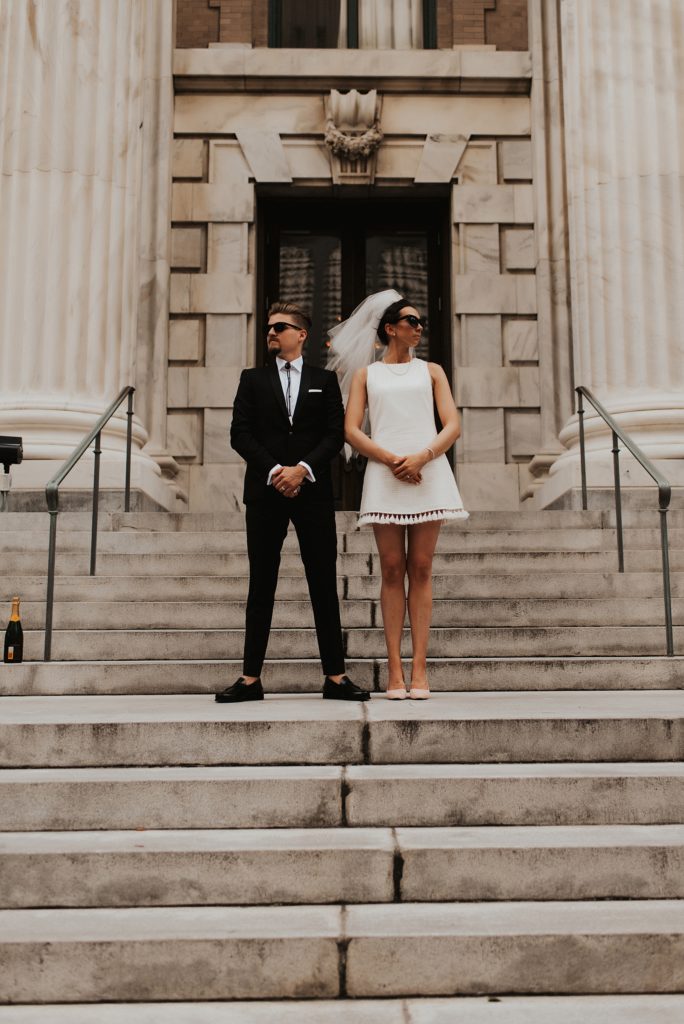 Blue brothers inspired bridal portrait of bride in short white dress on Le Meridien Steps