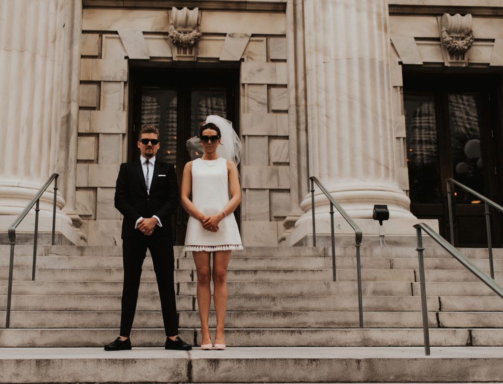 Blue brothers inspired bridal portrait of bride in short white dress on Le Meridien Steps