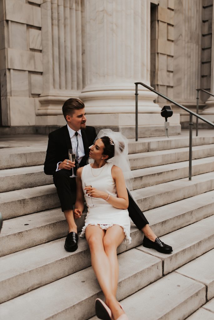 Bride in short white dress and groom sitting on Le Meridien Tampa steps
