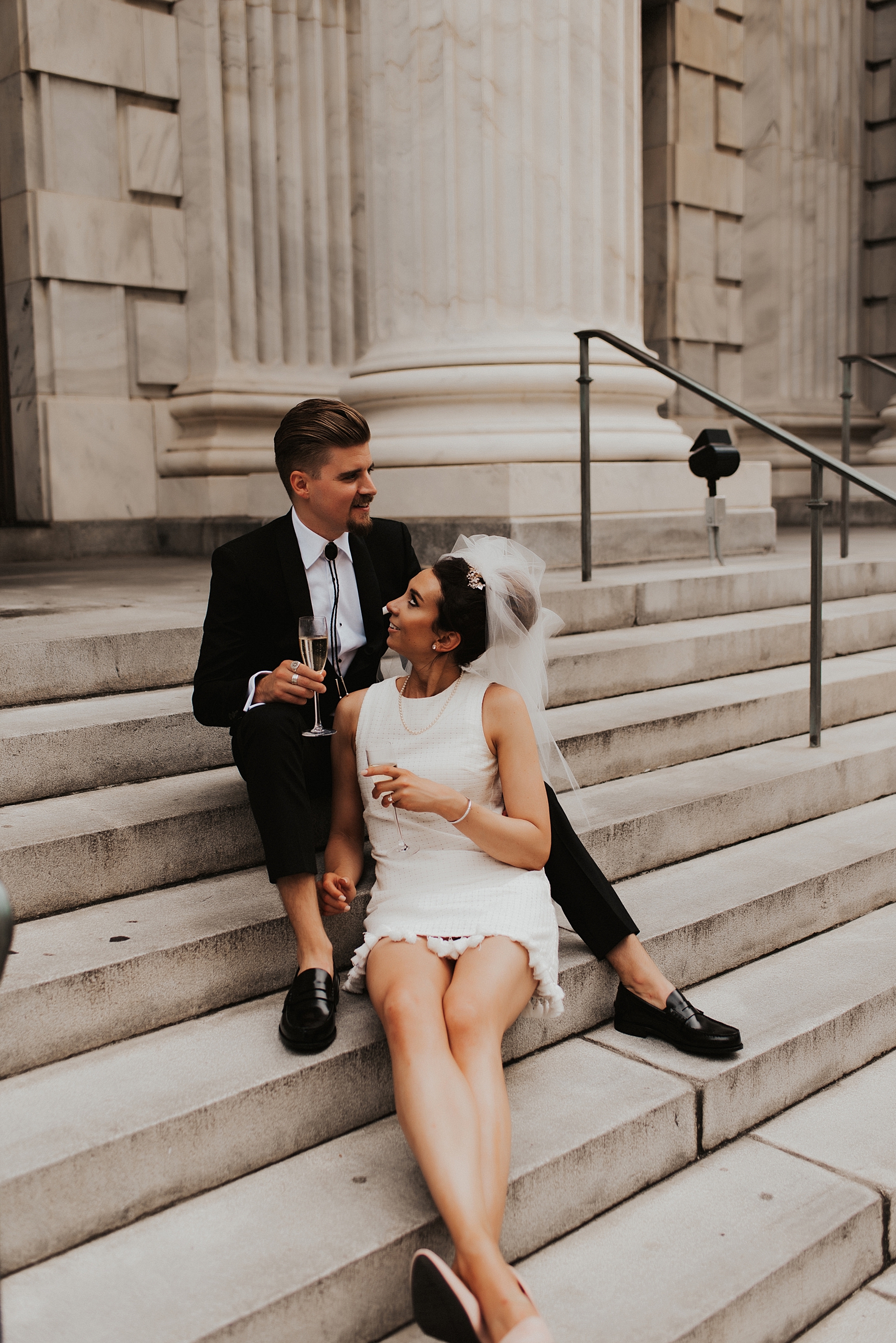 Bride in short white dress and groom sitting on Le Meridien Tampa steps