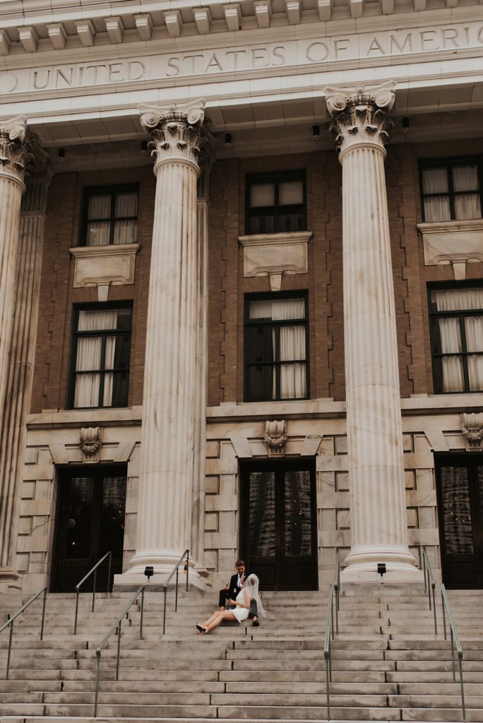 Bride in short white dress and groom sitting on Le Meridien Tampa steps
