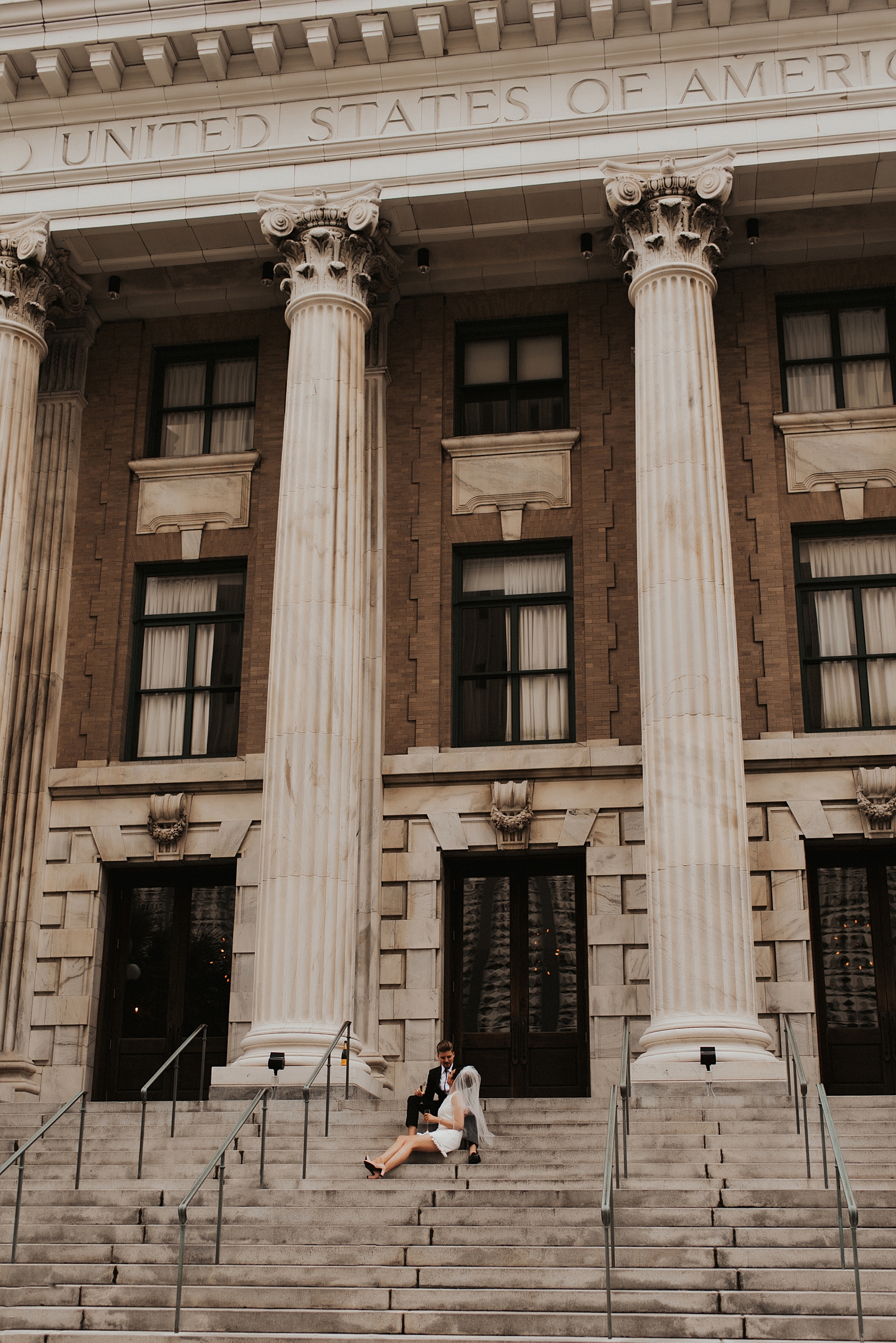 Bride in short white dress and groom sitting on Le Meridien Tampa steps