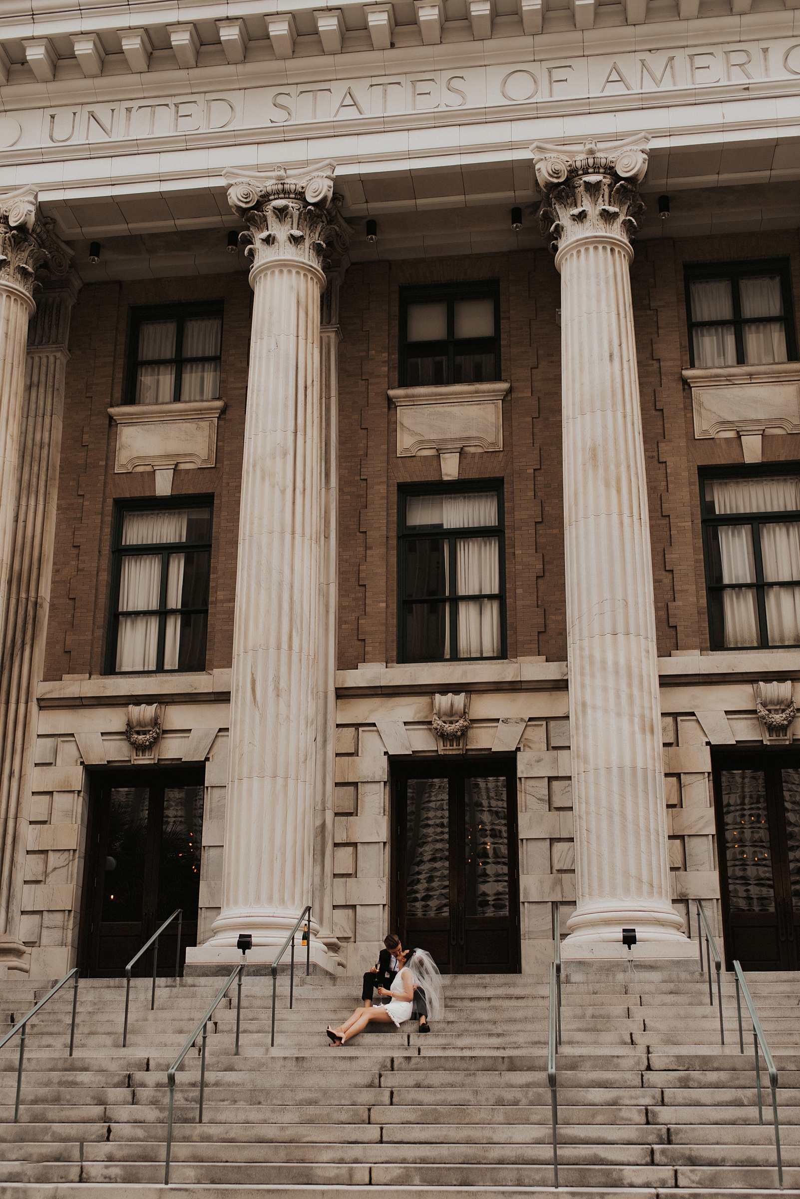Bride in short white dress and groom sitting on Le Meridien Tampa steps
