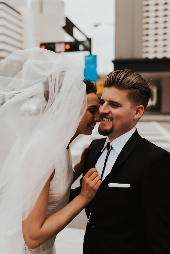Bride nuzzling into grooms cheek on downtown street
