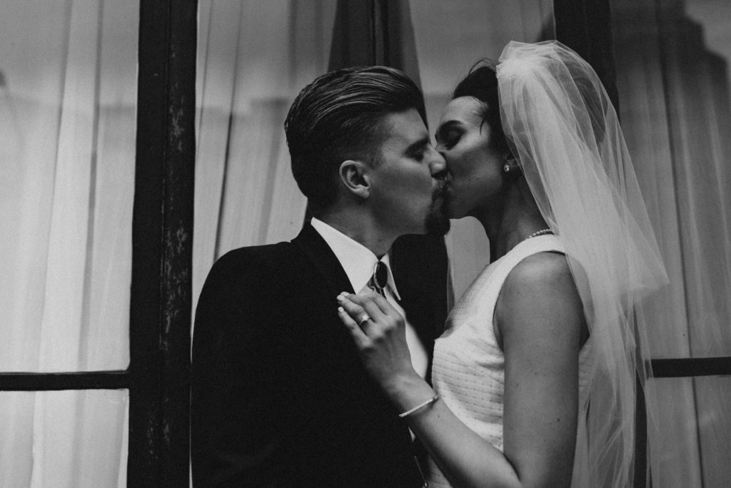 Bride and groom kissing in front of downtown Tampa window
