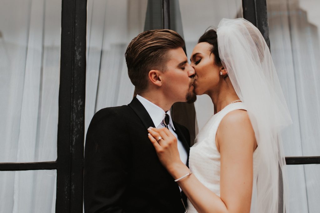 Bride and groom kissing in front of downtown Tampa window