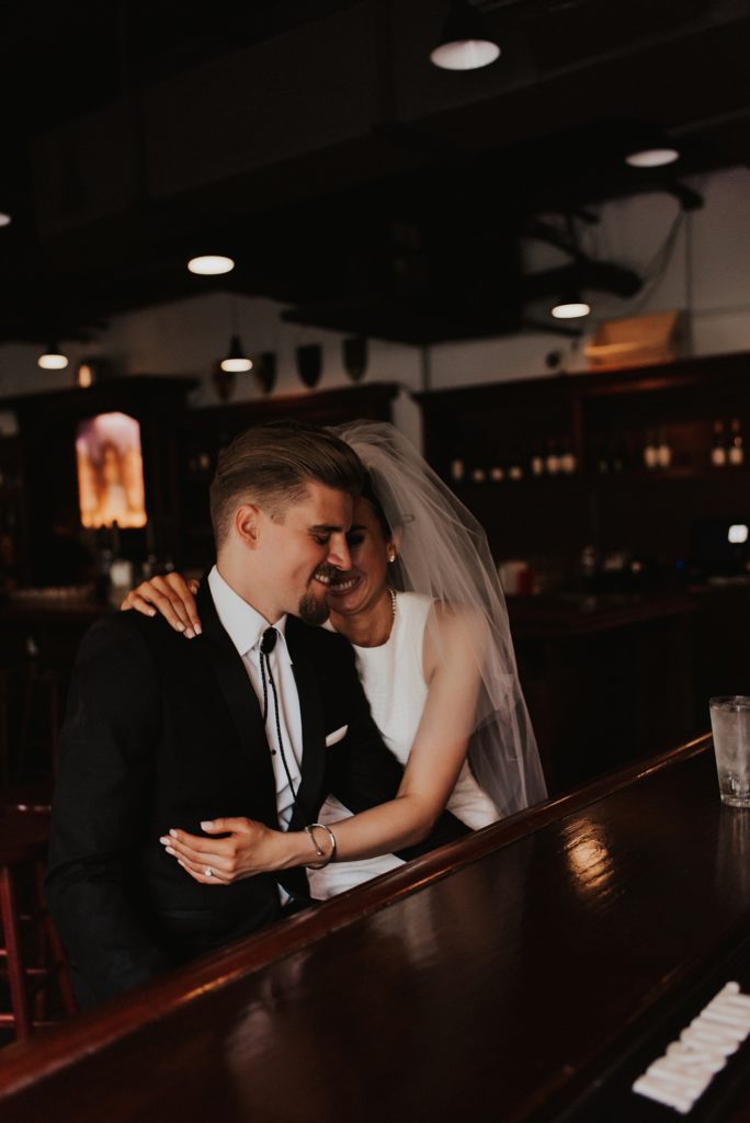 Bride whispering into grooms ear in downtown tampa bar
