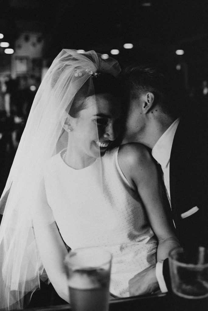 Groom whispering into brides ear