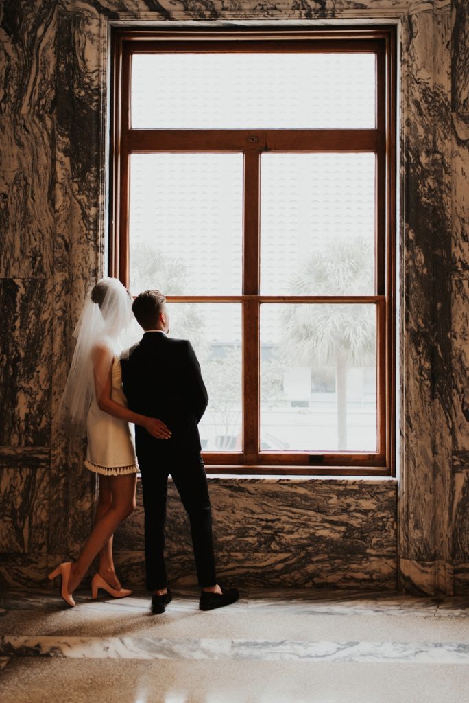 Bride in short white dress standing next to groom