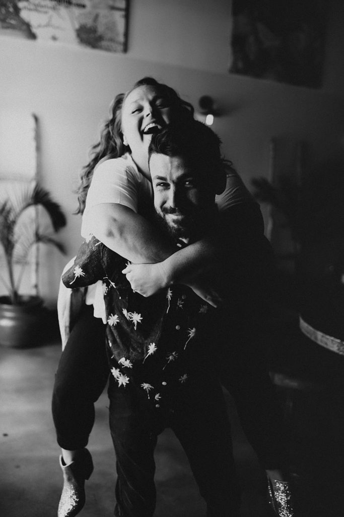 Couple giving piggy back ride during engagement session at brewery