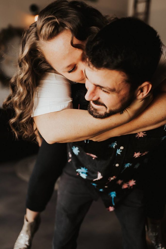 Couple giving piggy back ride during engagement session at brewery