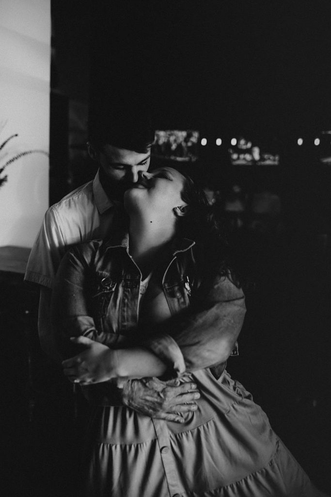 Couple cuddling during engagement session inside brewery
