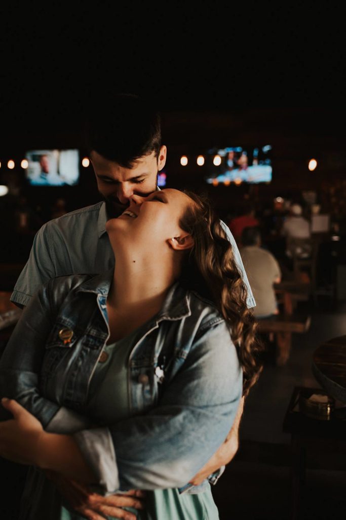 Couple cuddling during engagement session inside brewery