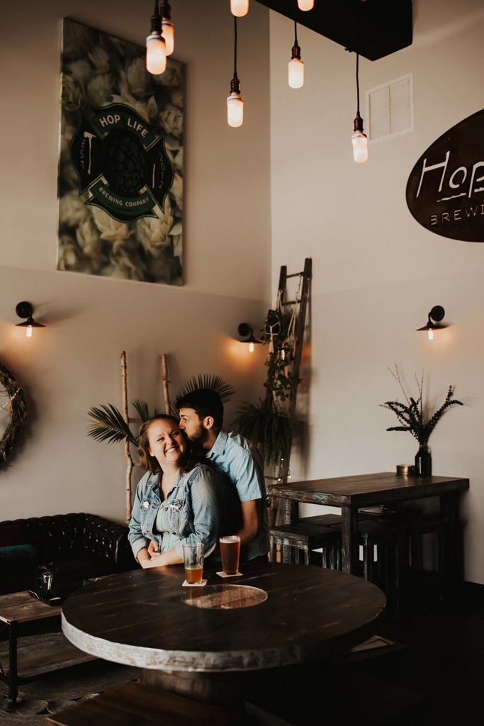 Couple hugging during engagement session inside brewery