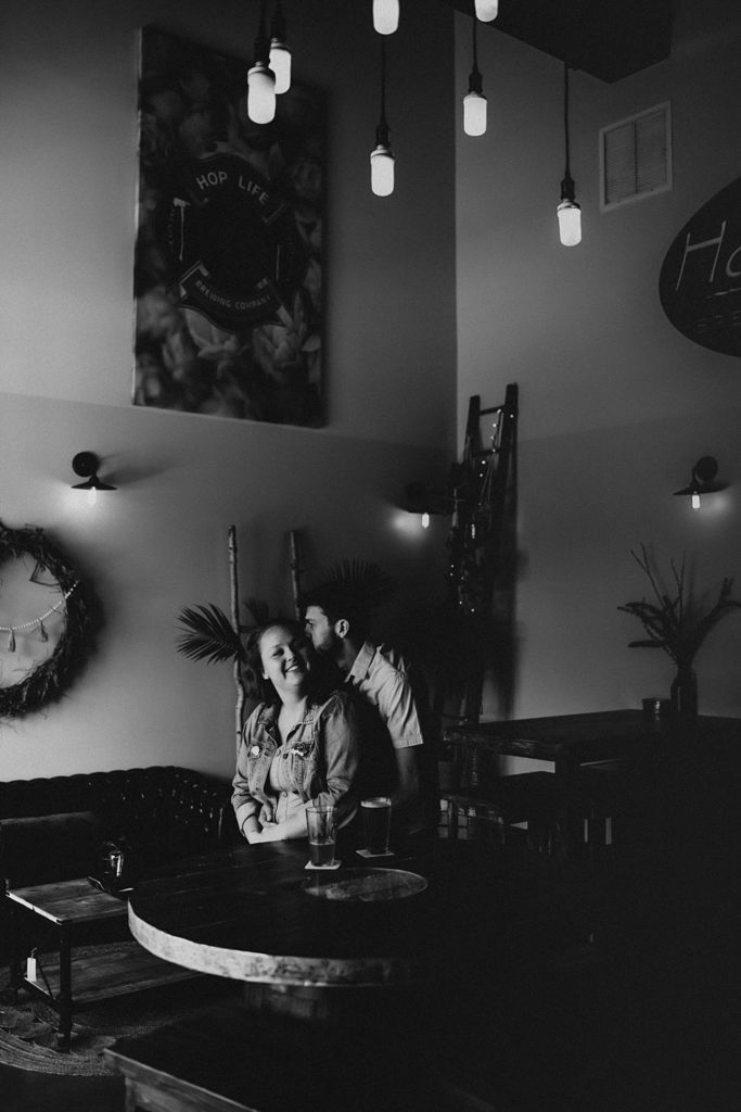 Couple hugging during engagement session inside brewery