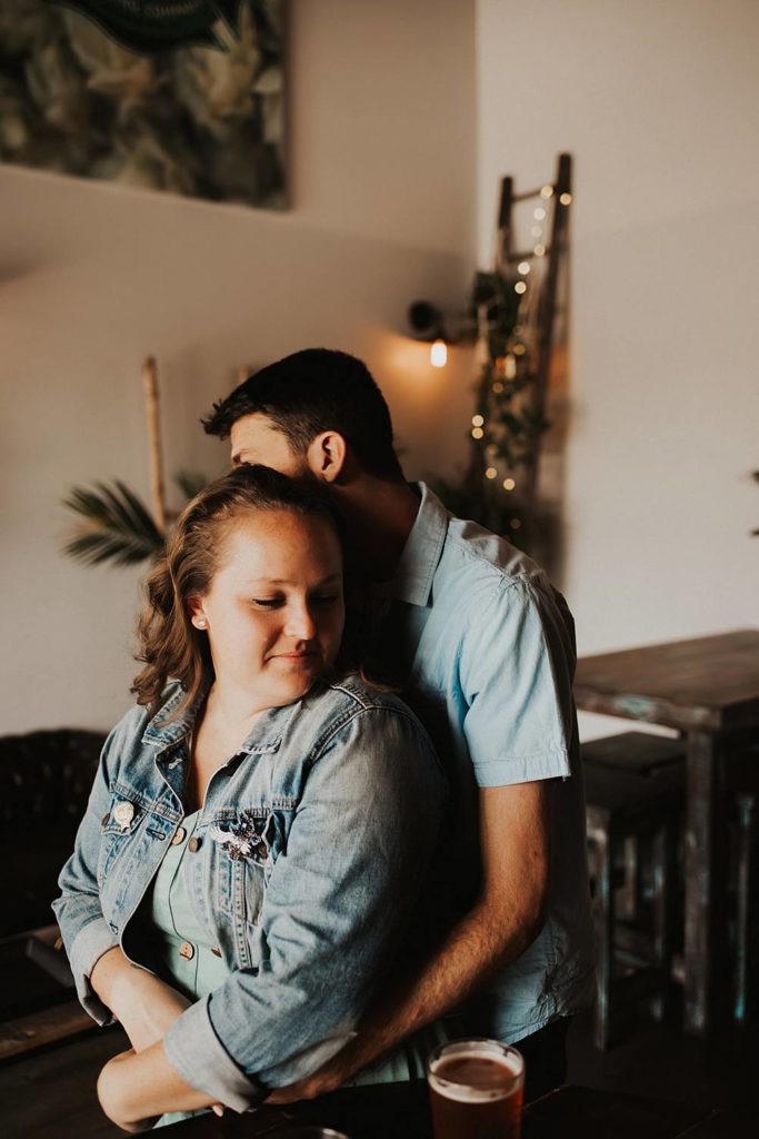 Couple hugging during engagement session inside brewery