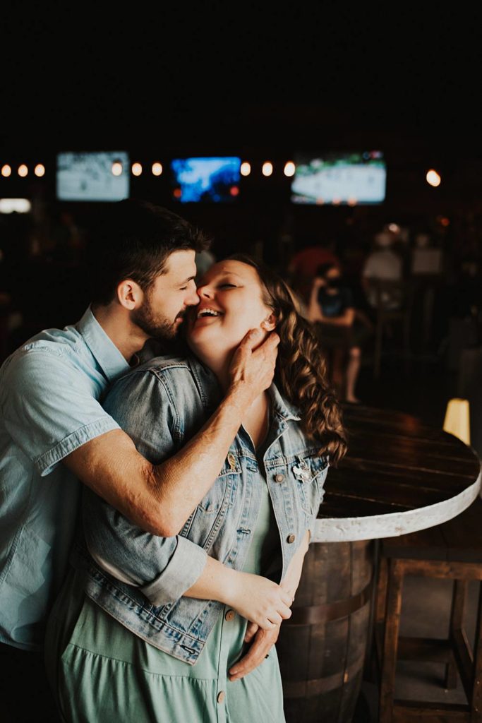 Couple kissing during engagement session inside brewery