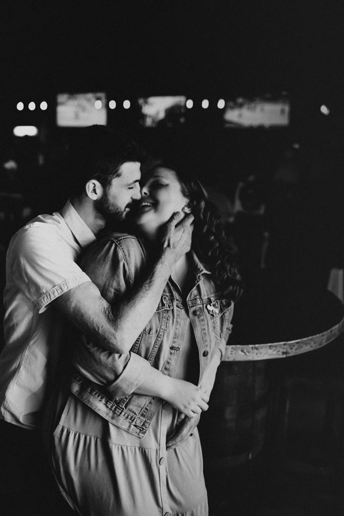 Couple kissing during engagement session inside brewery