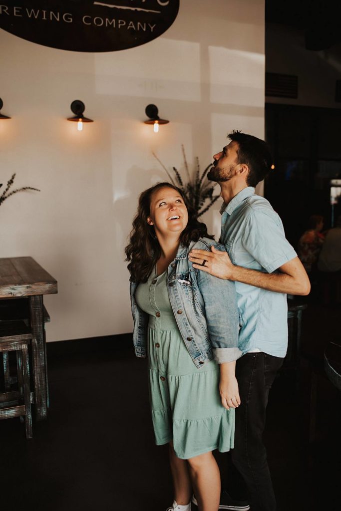 Couple laughing during engagement session inside brewery