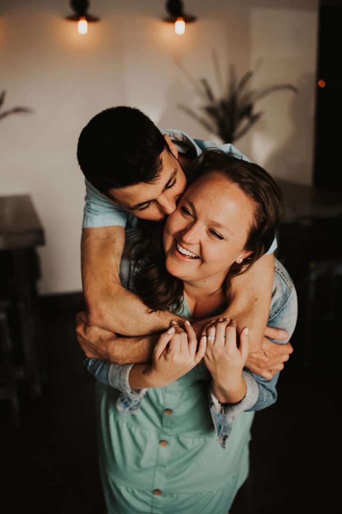 Couple laughing during engagement session inside brewery