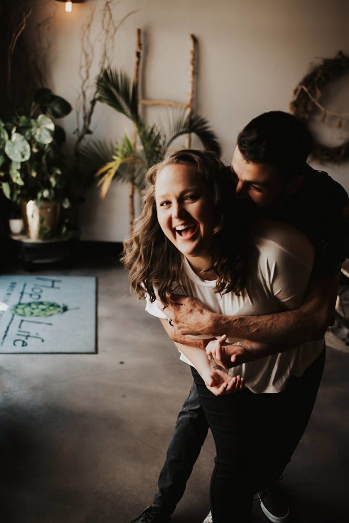 Boy grabbing girl from behind during engagement session at brewery
