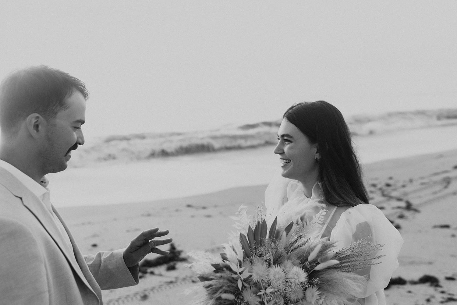 Bride and groom exchanging rings on beach