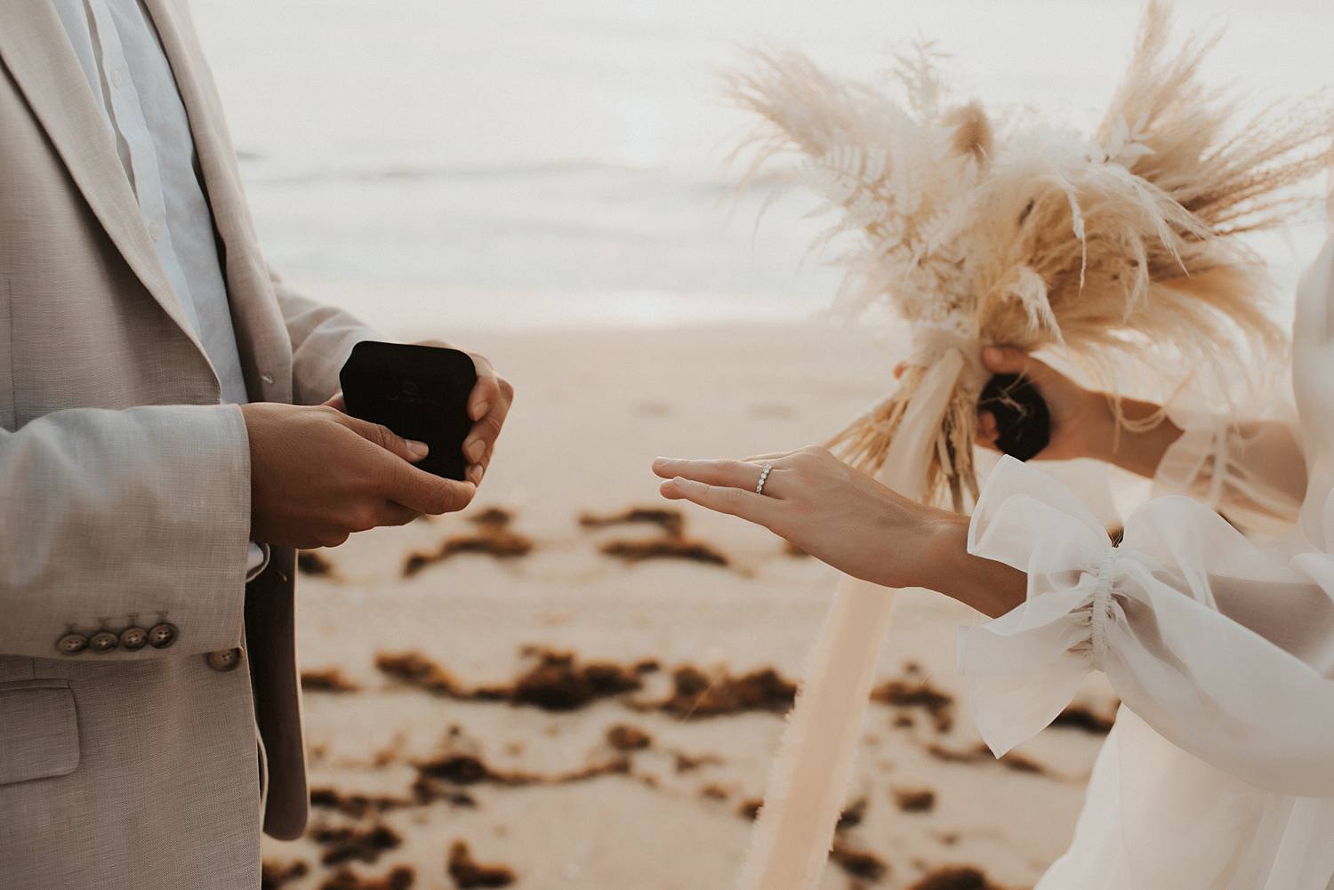 Bride and groom exchanging rings on beach