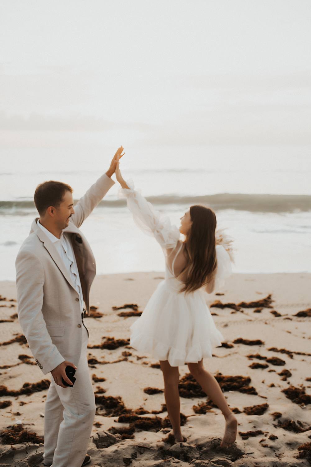 Bride and groom high fiving on beach