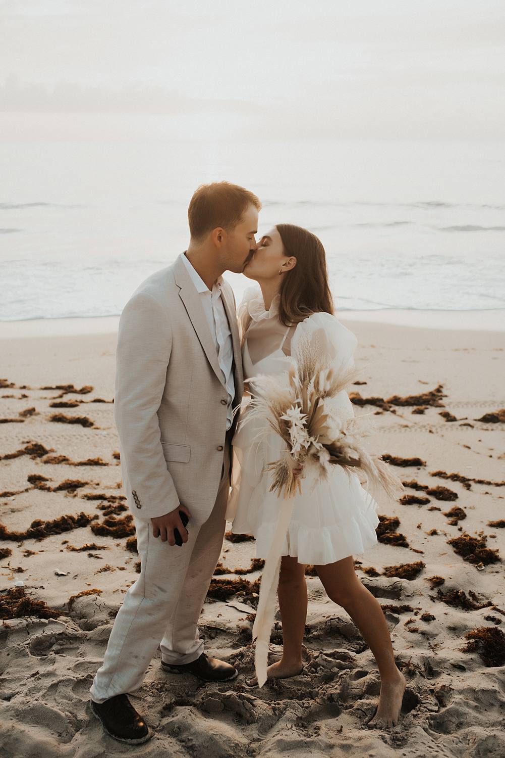 Bride and groom first kiss on beach