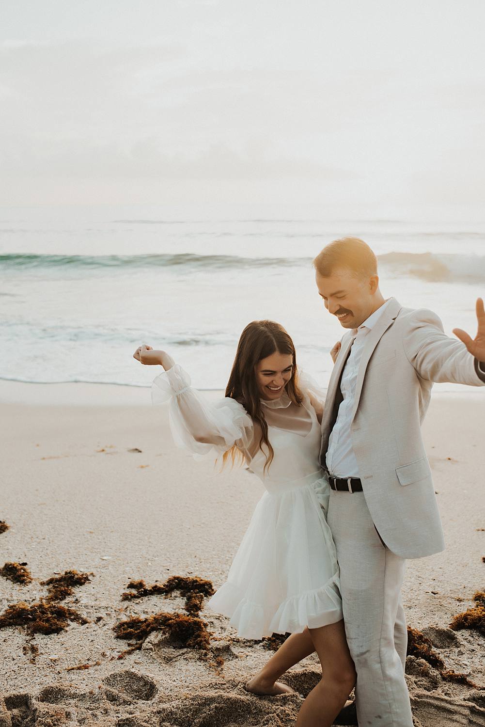 Bride and groom dancing on beach