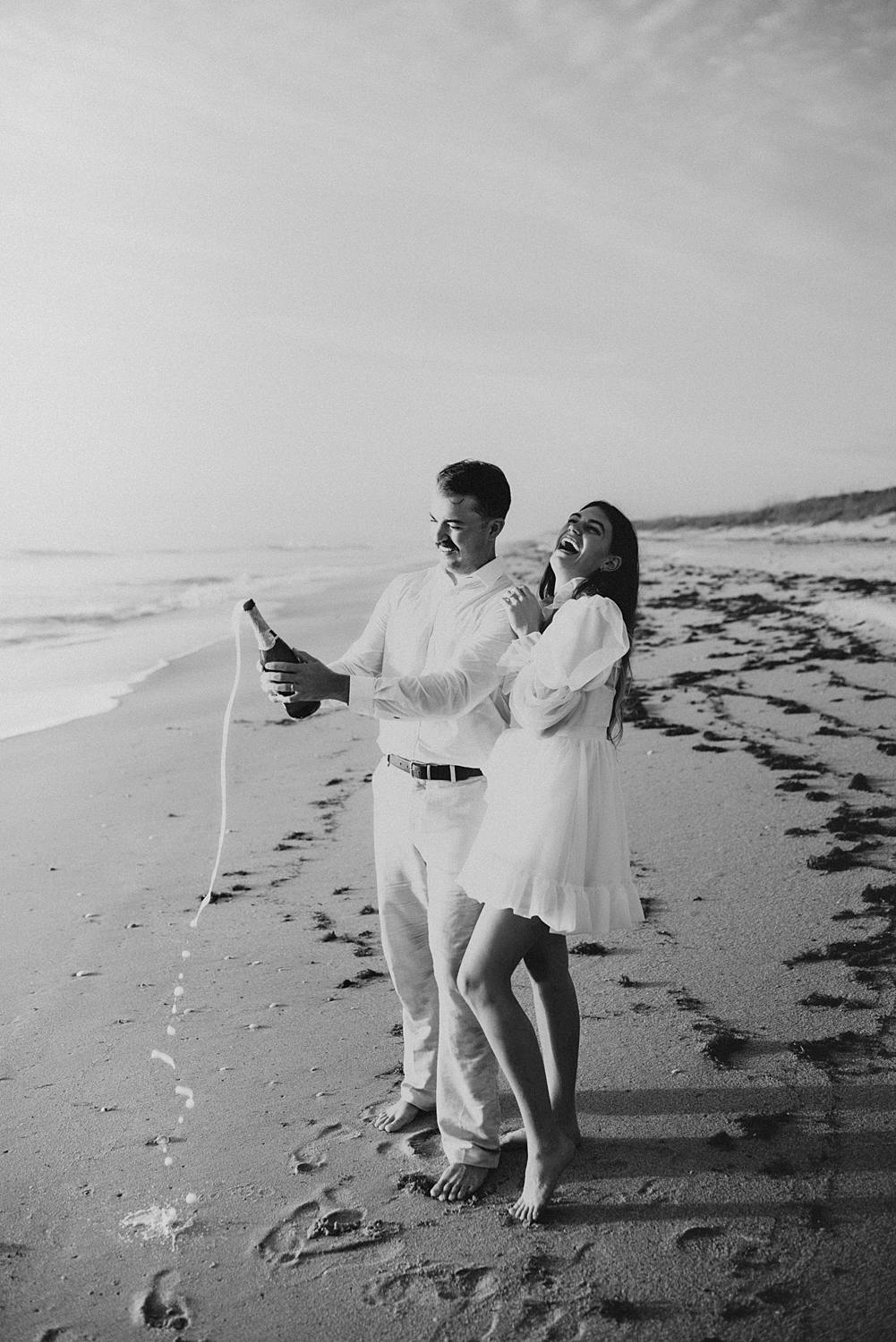 Bride and groom popping champagne on beach