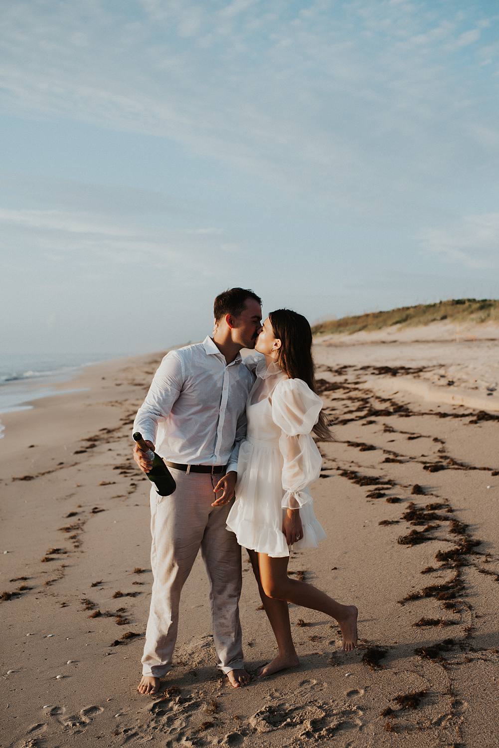 Bride and groom popping champagne on beach