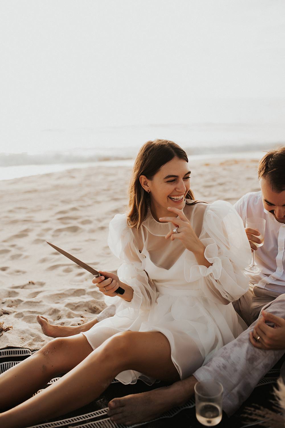 Bride cutting cake during elopement picnic on beach