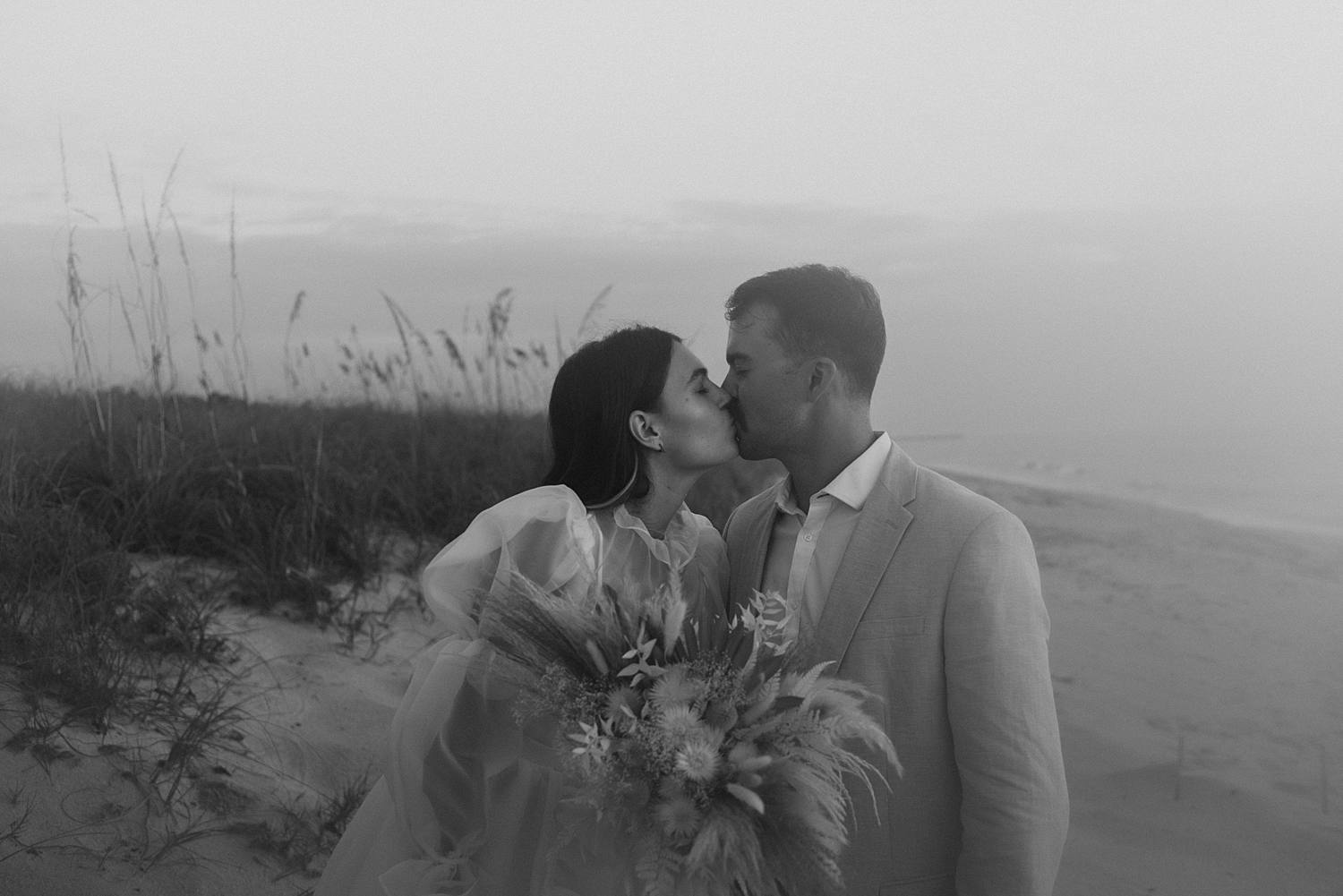 Bride and groom kissing on beach