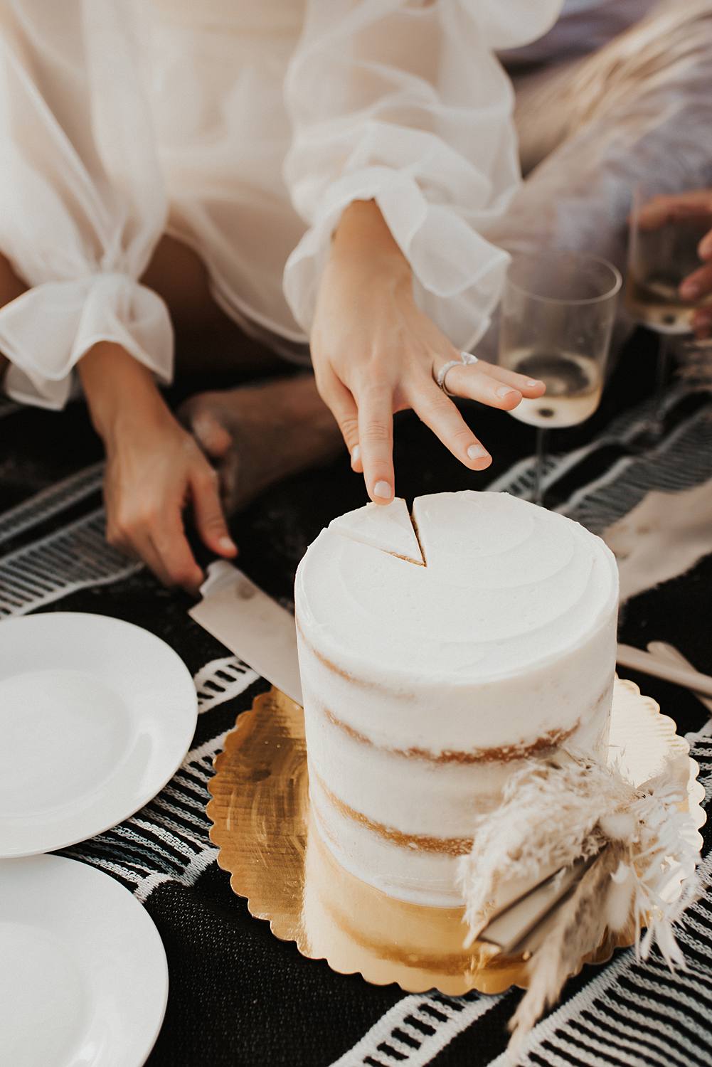 Bride cutting cake during elopement picnic on beach