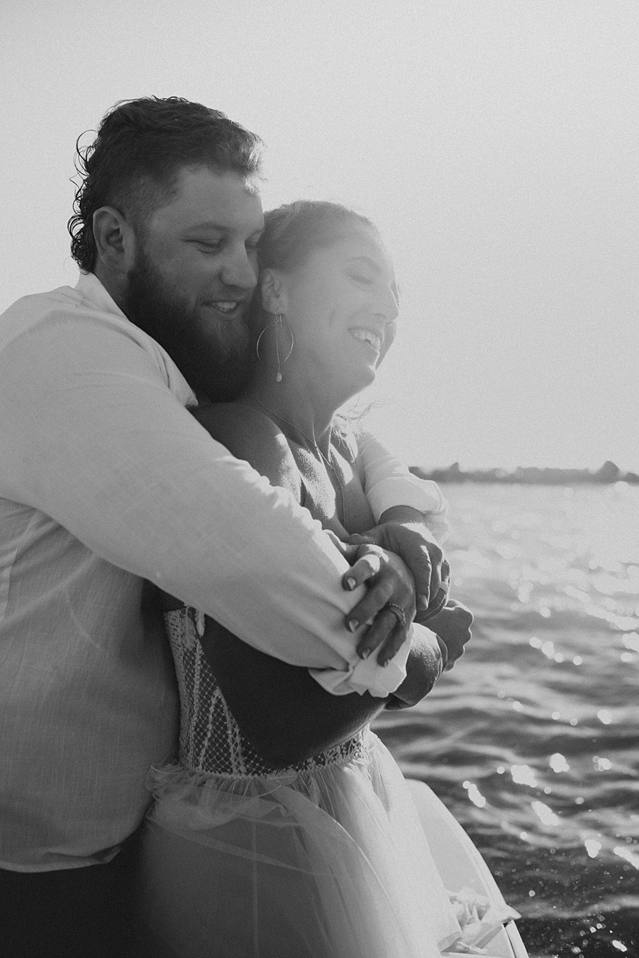 Groom hugging bride from behind on boat