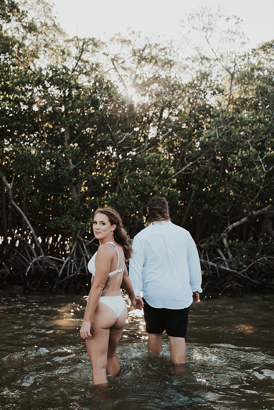 Groom leading bride into mangroves during elopement