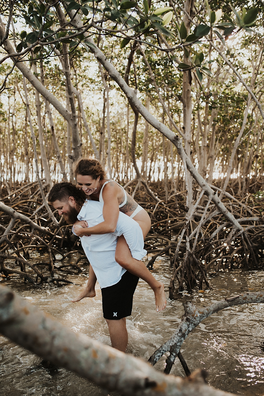 Bride on groom's back in mangrove trees