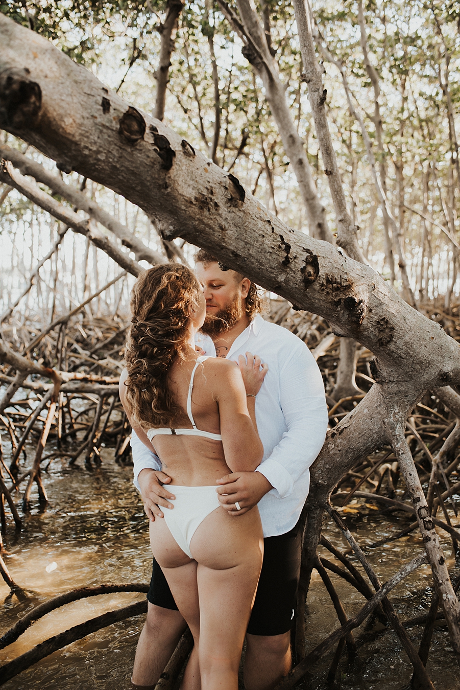 Bride in bikini kissing groom in mangroves