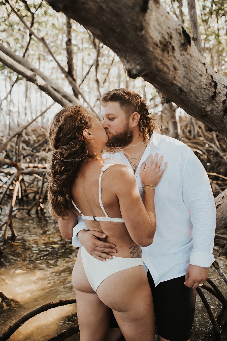Bride in bikini kissing groom in mangroves