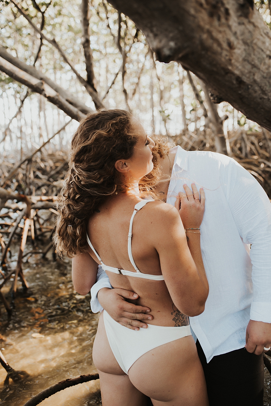 Bride in bikini kissing groom in mangroves