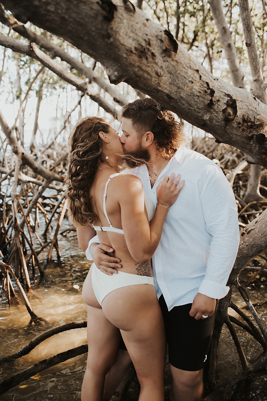 Bride in bikini kissing groom in mangroves