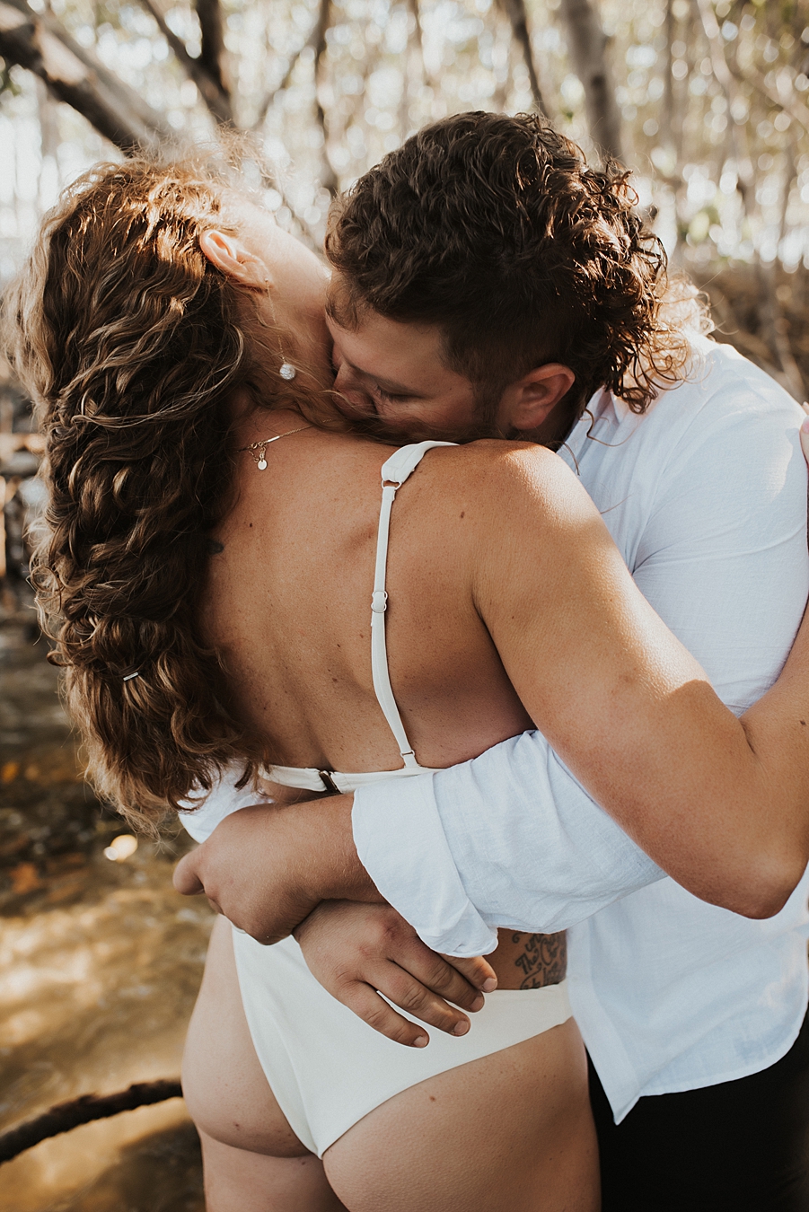 Bride in bikini kissing groom in mangroves