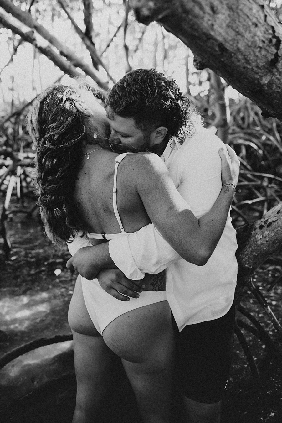 Bride in bikini kissing groom in mangroves