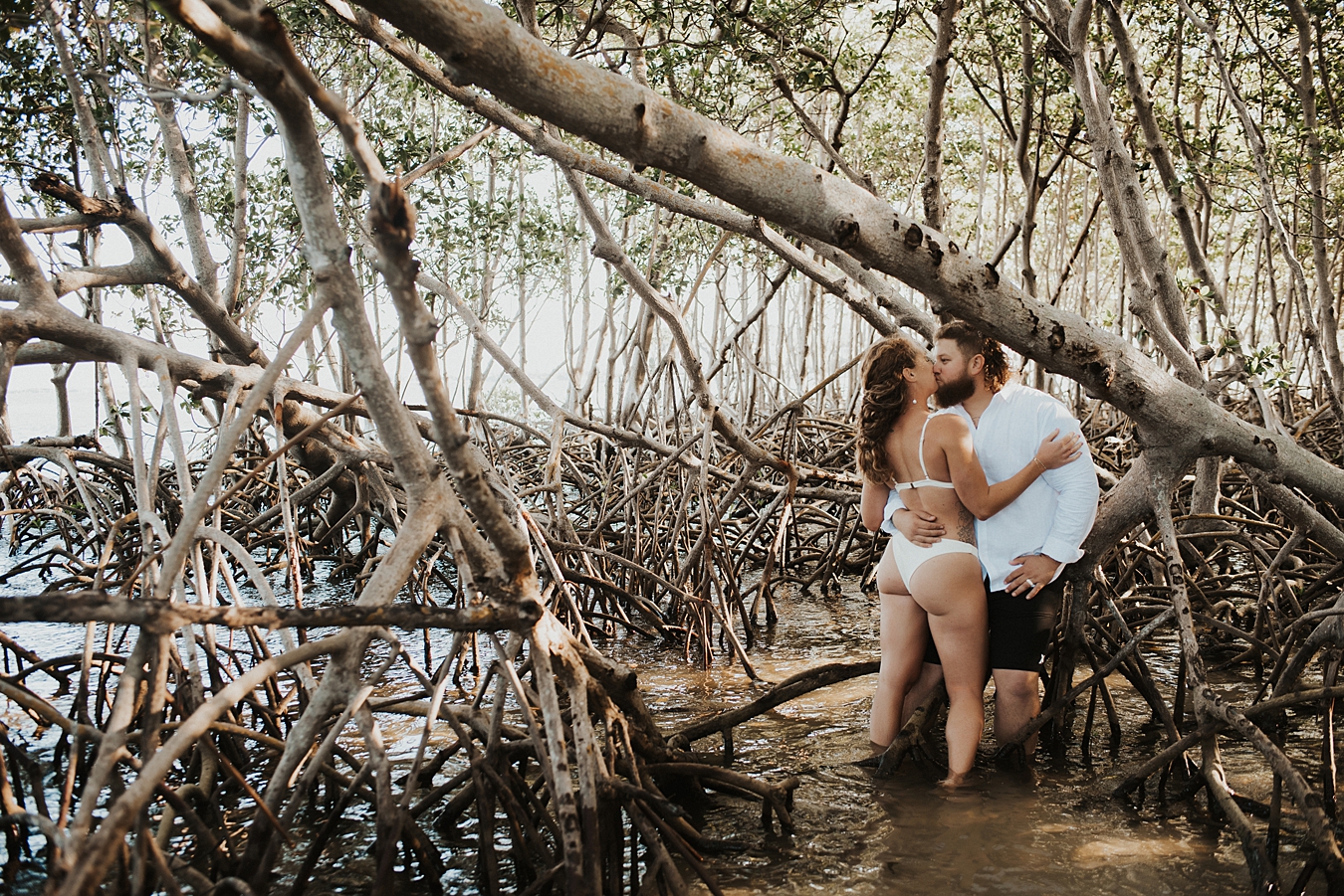 Groom lifting bride in white bikini in mangrove trees