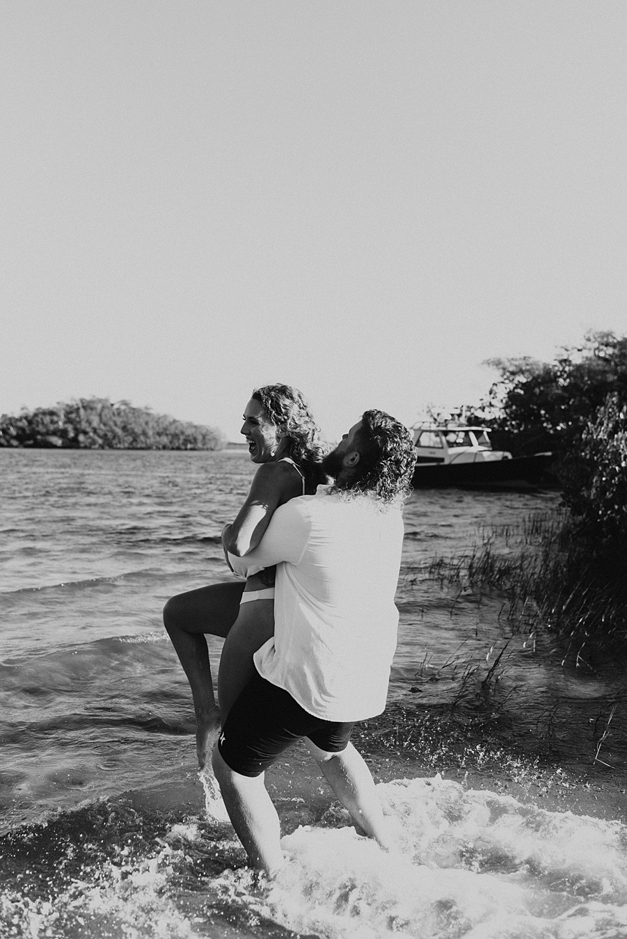 Groom lifting bride into the air in the water