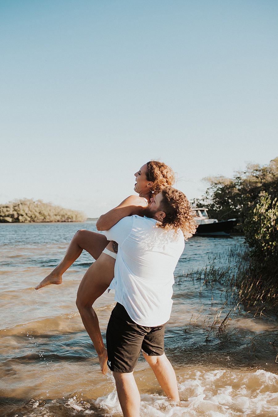 Groom lifting bride into the air in the water
